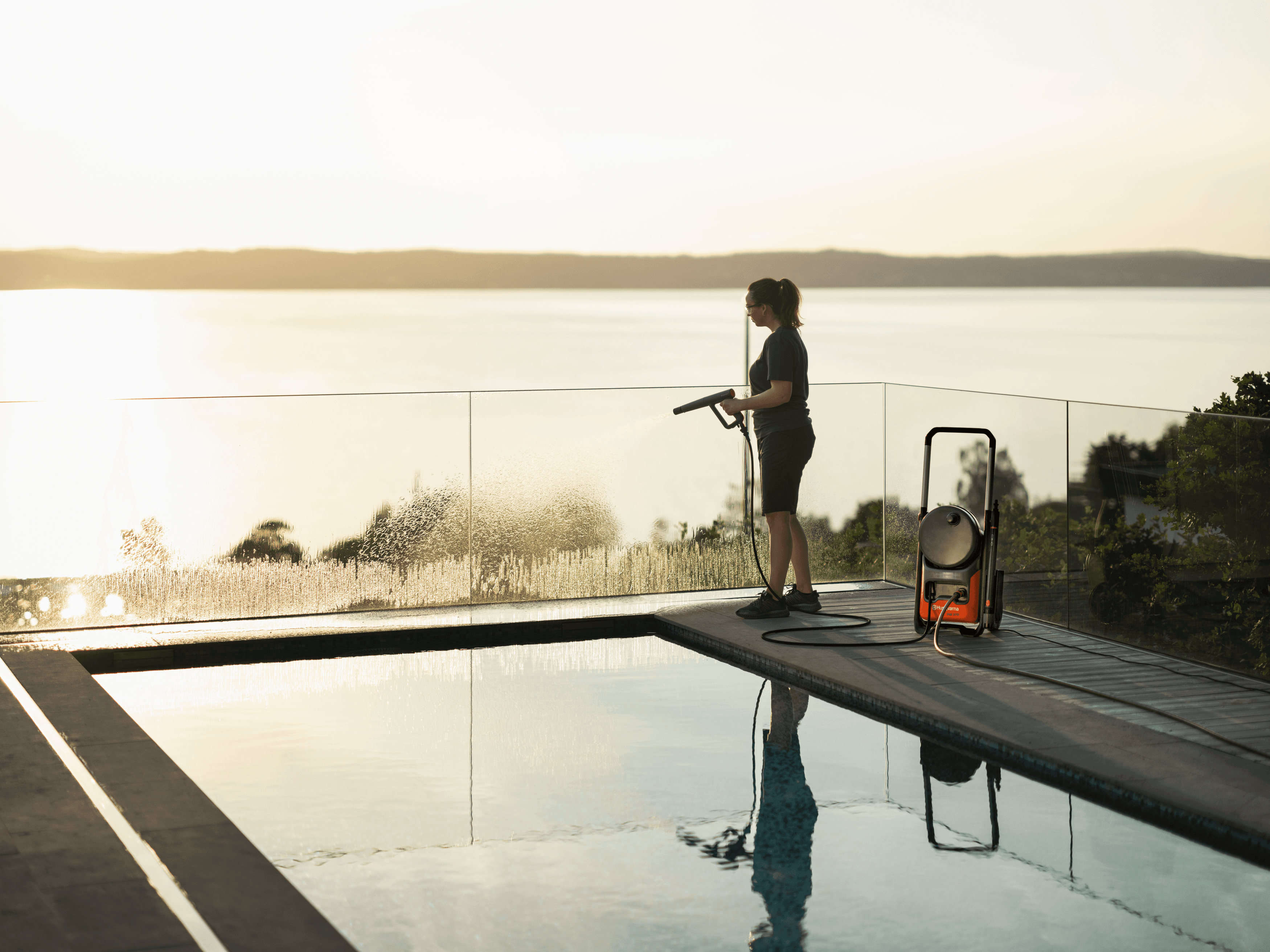 Automower sitting in grass patch in backyard with family cooking bbq in background